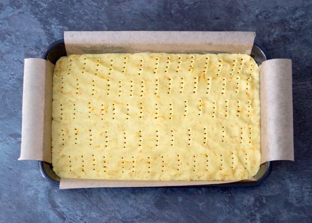 Chocolate Orange Caramel Shortbread: the biscuits base dough pressed into a baking tray and pricked with a fork