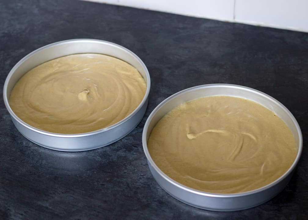 Rhubarb and custard cake batter in two lined sandwich tins