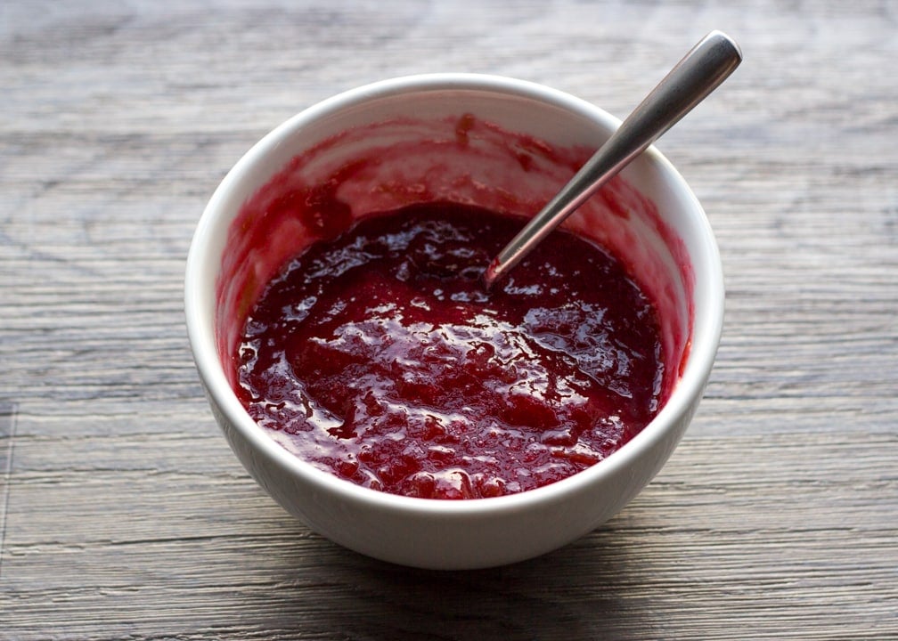 Rhubarb jam in a small bowl with a spoon