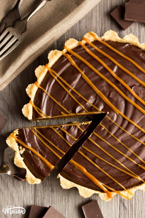No Bake Caramel Chocolate Tart Recipe: No bake caramel chocolate tart on a worktop with a piece on a cake slice