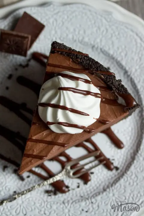 Close up of a slice of no bake chocolate cheesecake on a plate drizzled with sauce