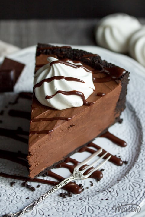 A slice of chocolate cheesecake on a plate drizzled with chocolate sauce