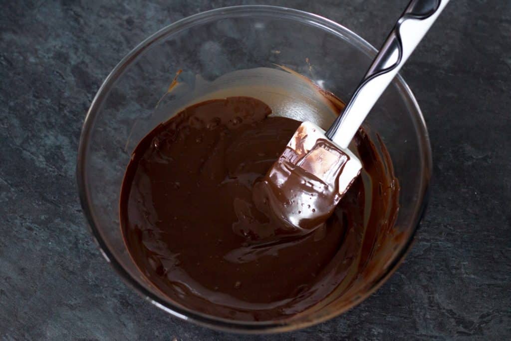 Melted chocolate in a glass bowl with a spatula