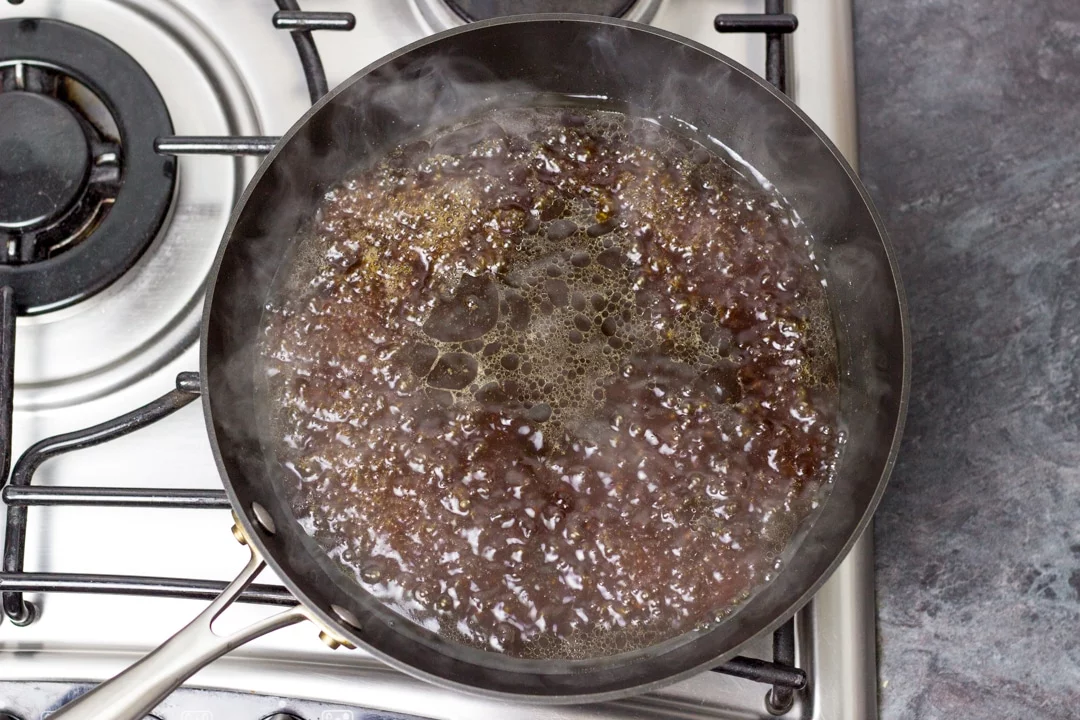 Bubbling chicken teriyaki sauce in a large frying pan