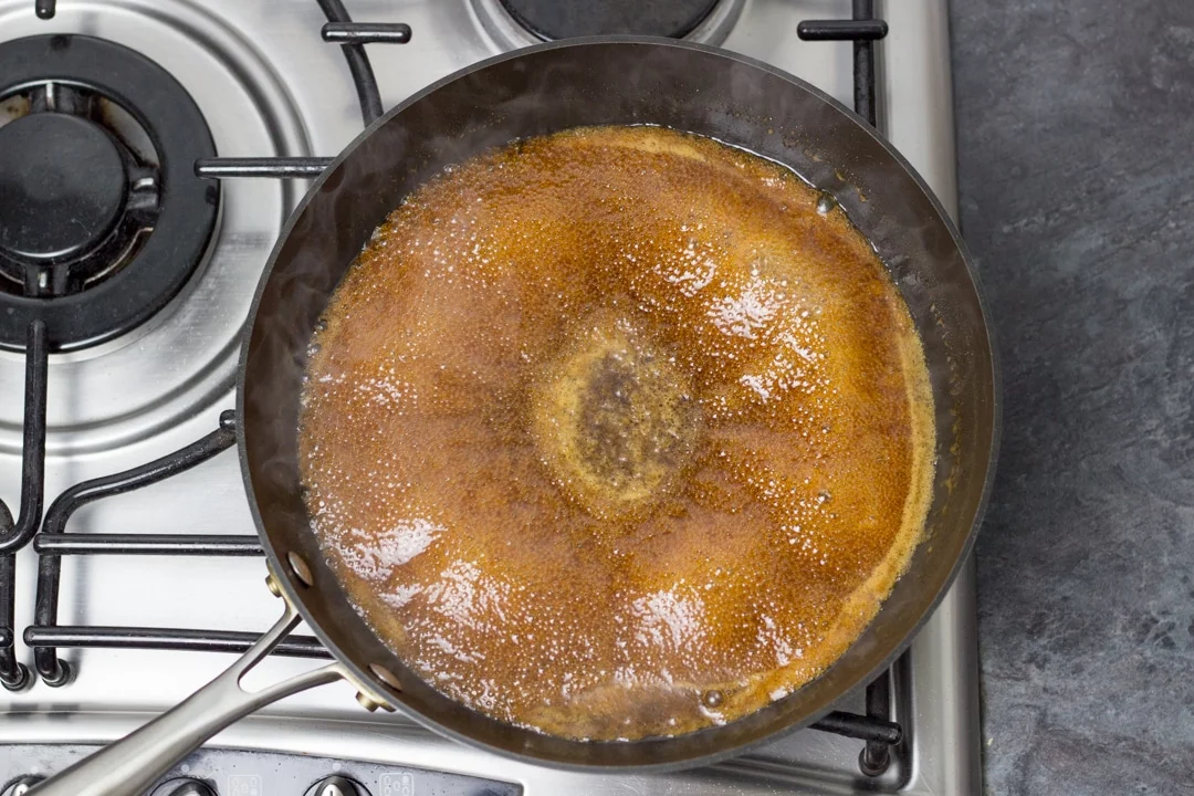 Boiling chicken teriyaki sauce in a large frying pan