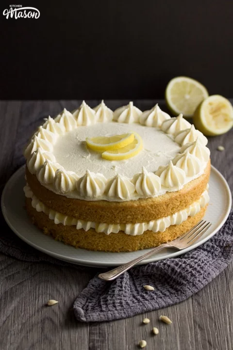 dairy free / vegan lemon cake on a plate with a fork and squeezed lemons