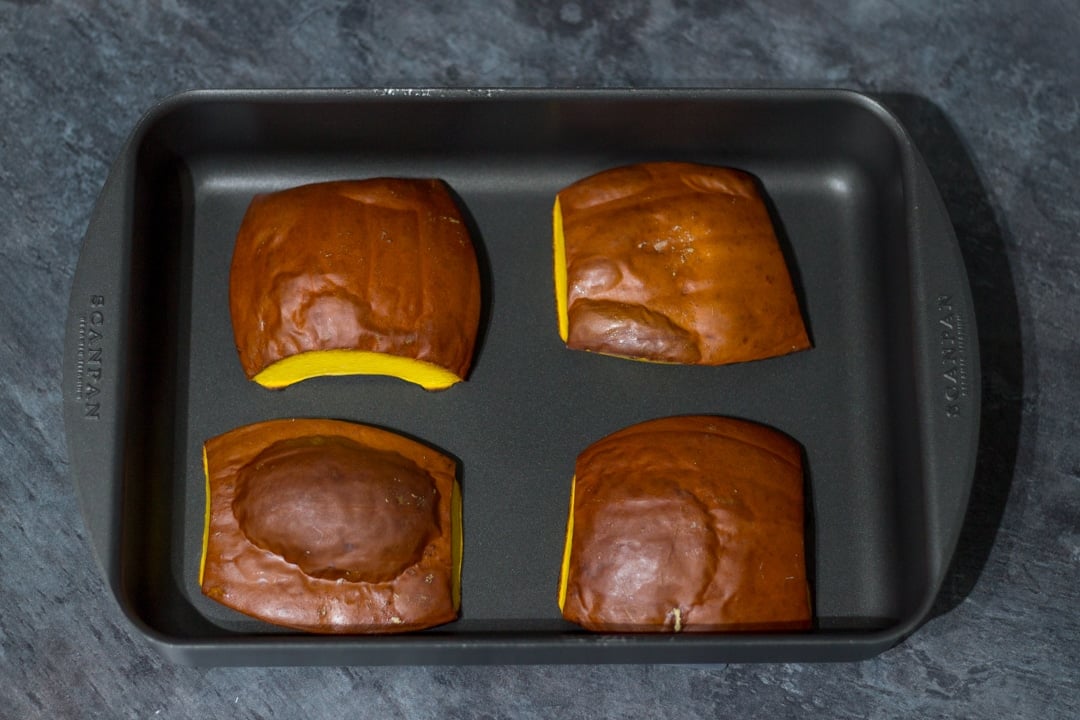 roasted pumpkin quarters on a roasting pan