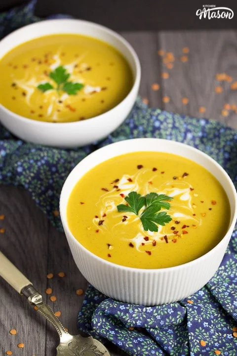 curried coconut lentil soup in a bowl with parsley and chilli flakes on top