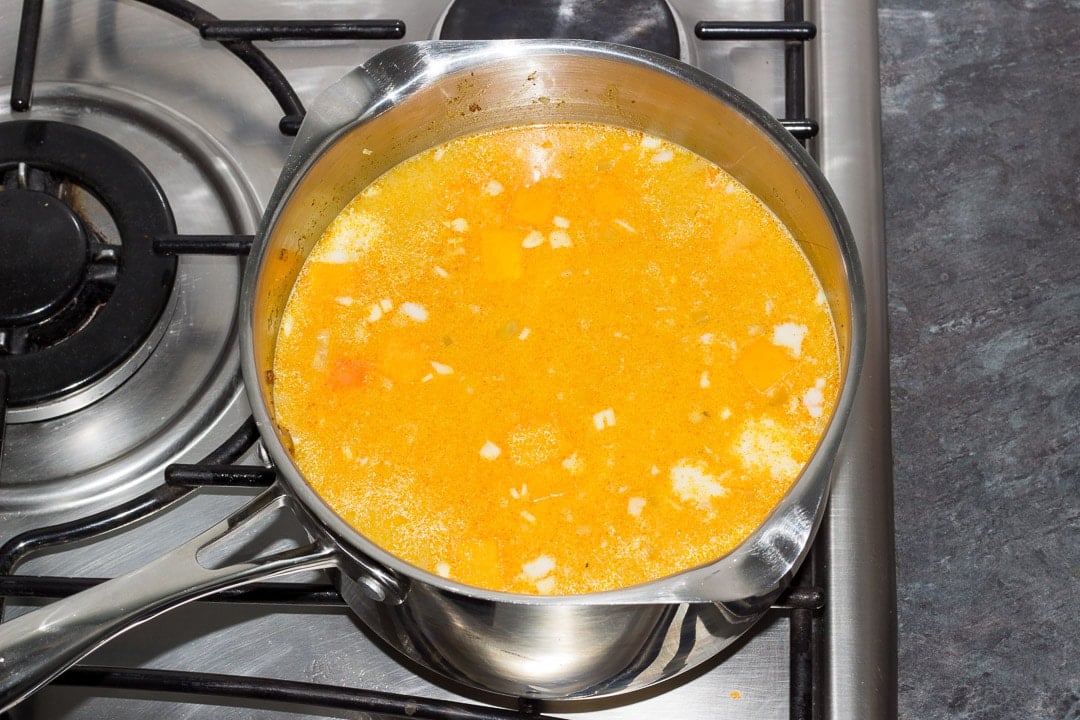 curried coconut lentil soup simmering in a large pot on the hob