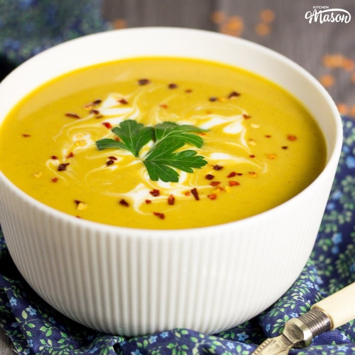 curried coconut lentil soup in a bowl with parsley and chilli flakes on top