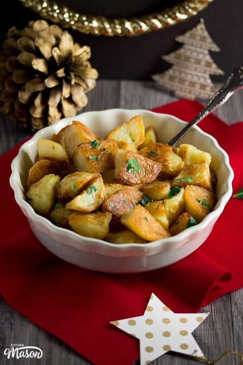 golden crispy roast potatoes in a dish scattered with parsley