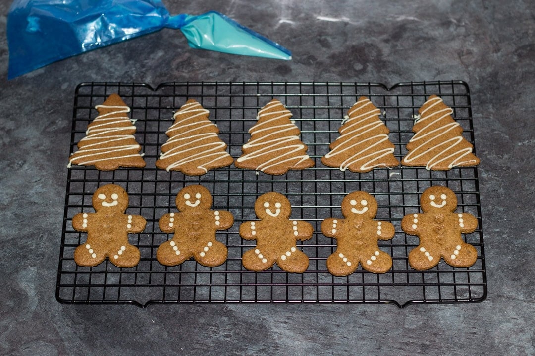 easy gingerbread recipe: baked gingerbread men on a cooling rack decorated with white chocolate