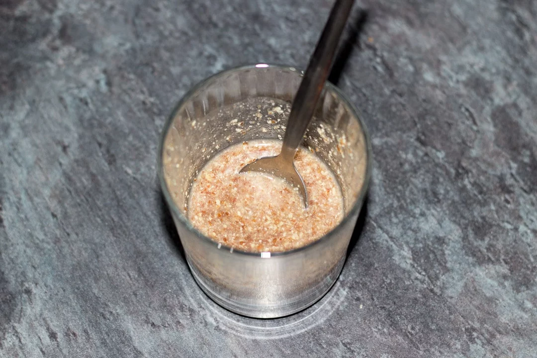 flaxseed mixed in water in a glass with a spoon