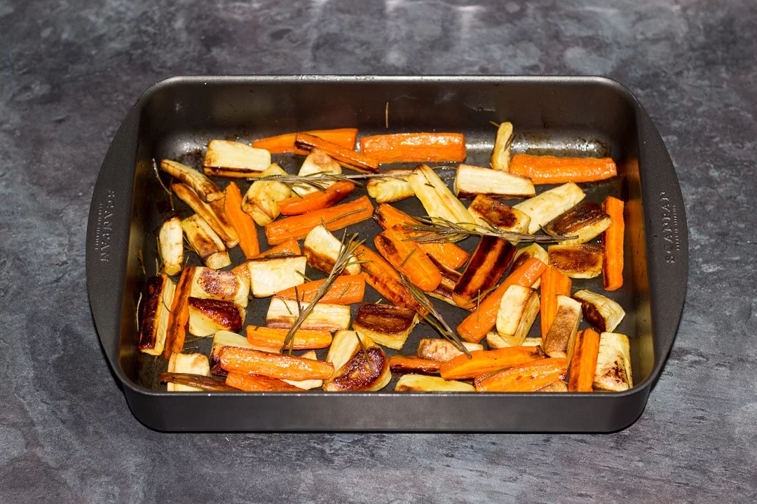 Honey roast parsnips and carrots with rosemary in a roasting tray