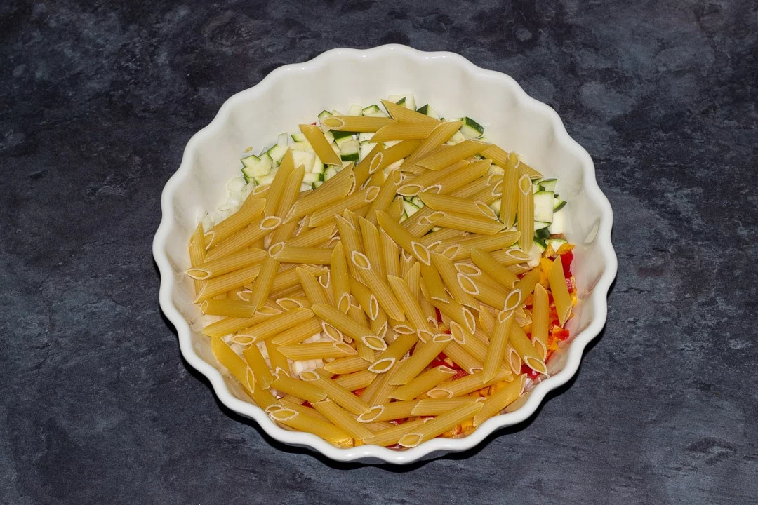 finely chopped vegetables in a baking dish with penne pasta
