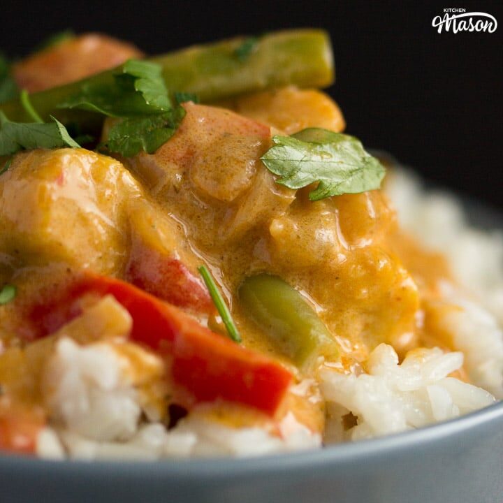 close up of vegetable thai red curry in a grey bowl with rice