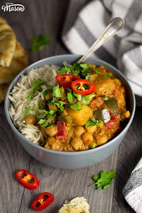 Slow cooker vegetable curry in a slow cooker in a bowl with rice, fresh coriander and fresh red chilli