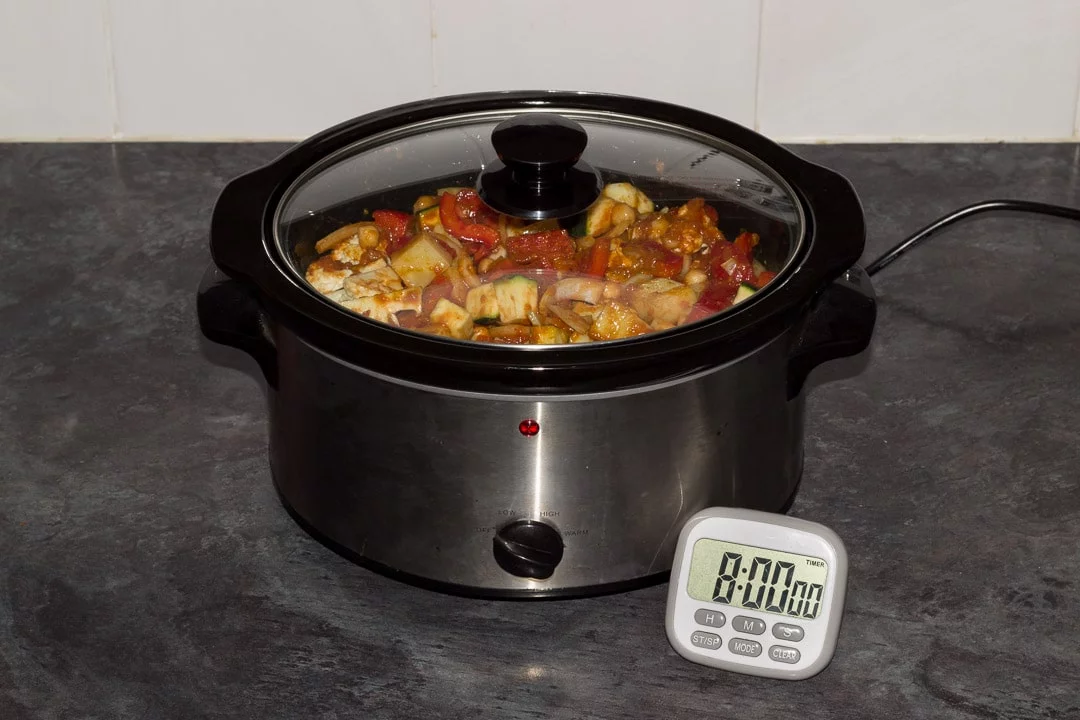 uncooked slow cooker vegetable curry with the lid on and a timer set for 8 hours