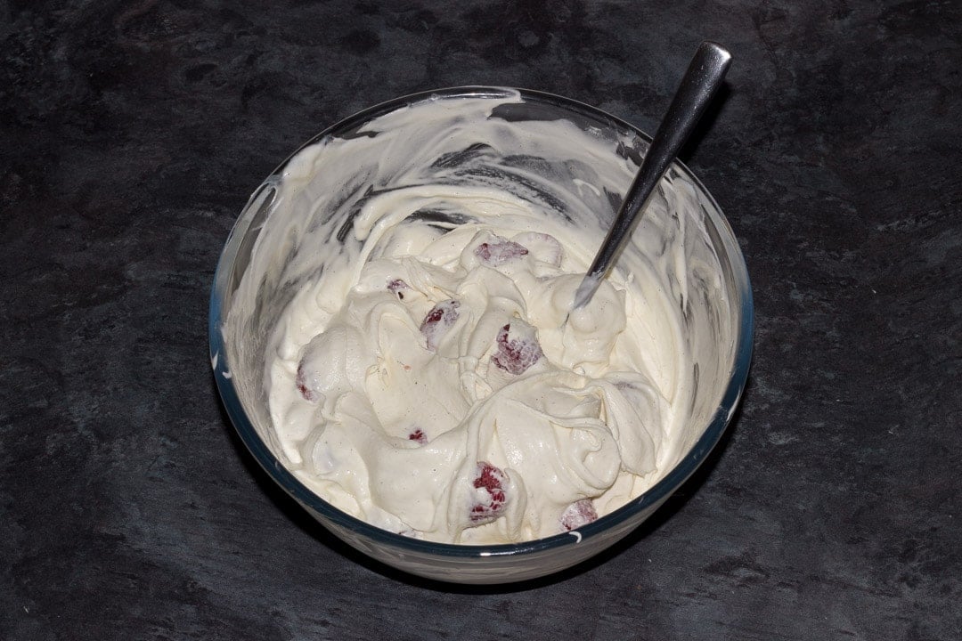 Dairy free vanilla ice cream in a glass bowl with raspberries mixed in