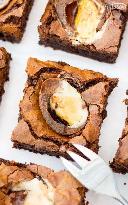 Creme Egg Brownies laid out on baking paper with a fork