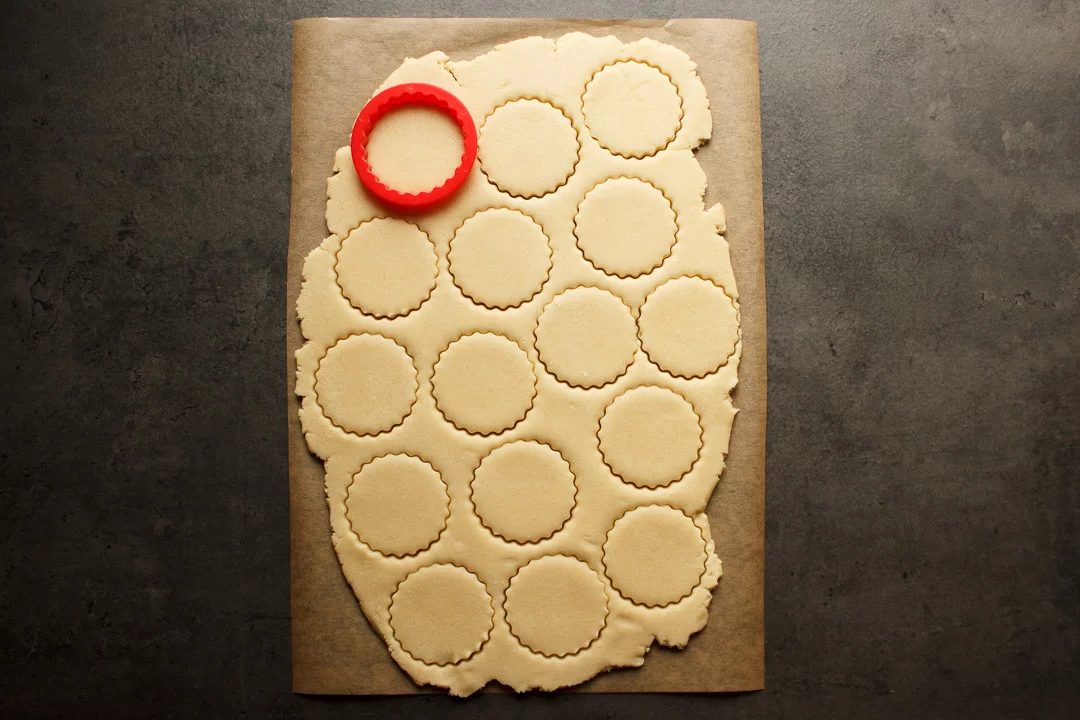 shortbread cookie dough rolled out with fluted circles cut out of it