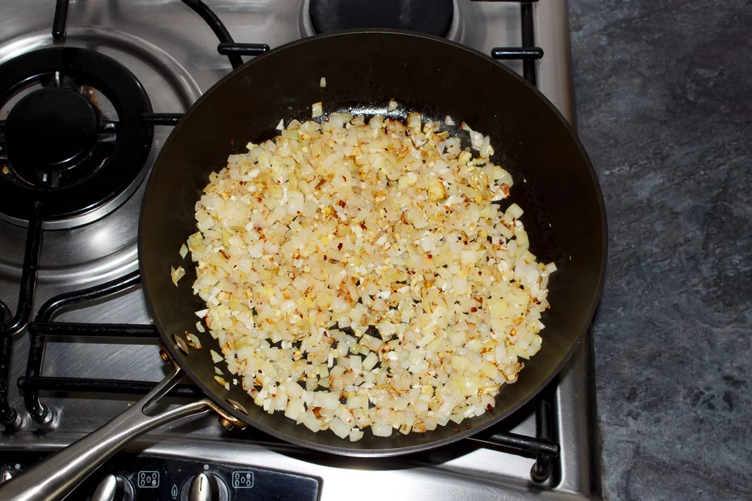 onions frying in a pan with garlic, ginger and chilli flakes