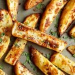 homemade wedges on a baking tray with fresh parsley scattered on top