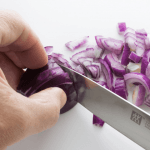 Red onion being diced with a sharp knife