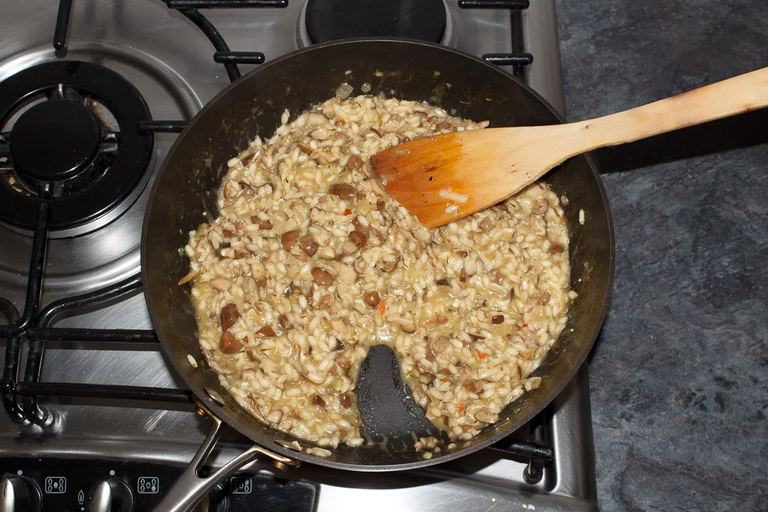 cooked wild mushroom risotto in a large saute pan with cheese melted through it