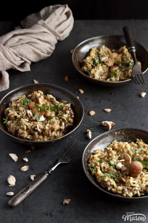 three bowls of wild mushroom risotto topped with fresh parsley