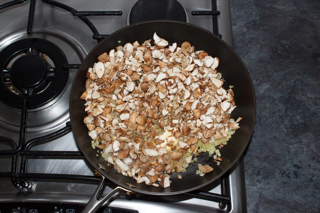 onion and mushrooms frying in a large saute pan