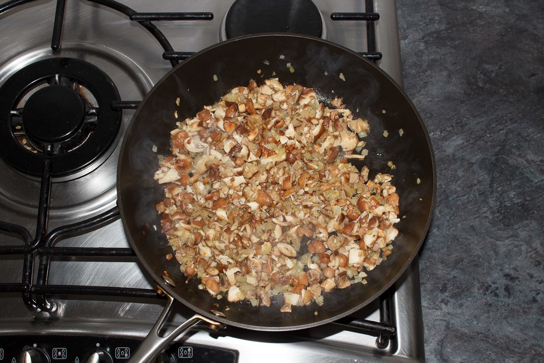onion and mushrooms frying in a large saute pan