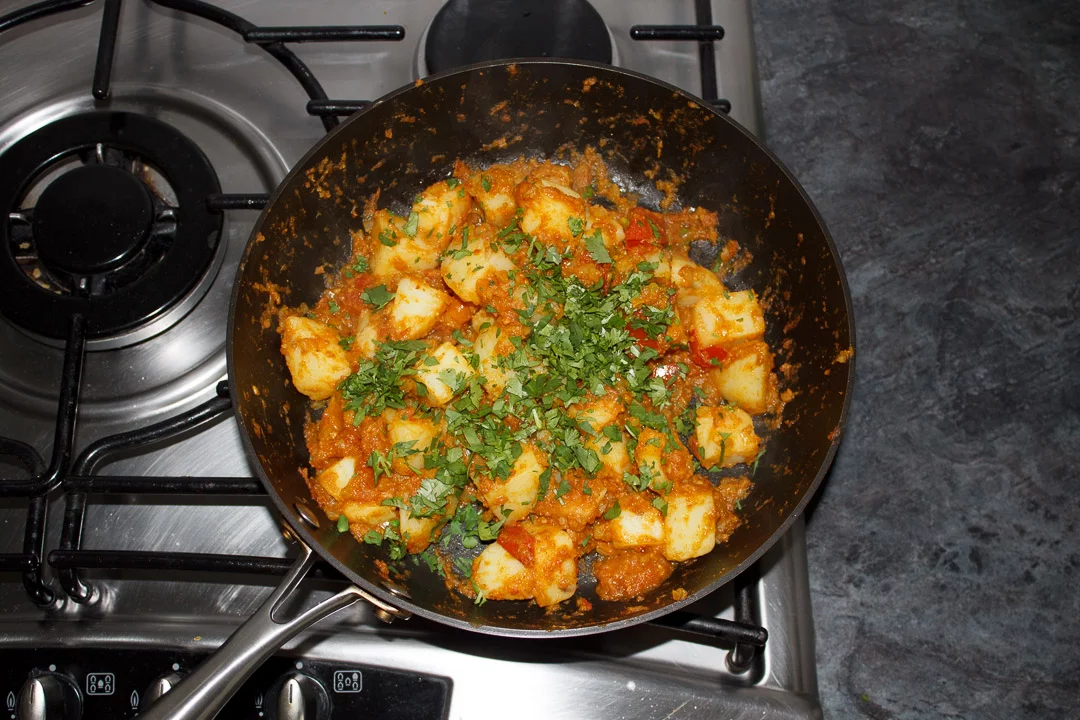 Bombay aloo in a large saute pan scattered with lots of coriander