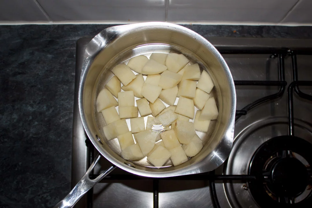 cubed potatoes in a saucepan covered in water on a stove