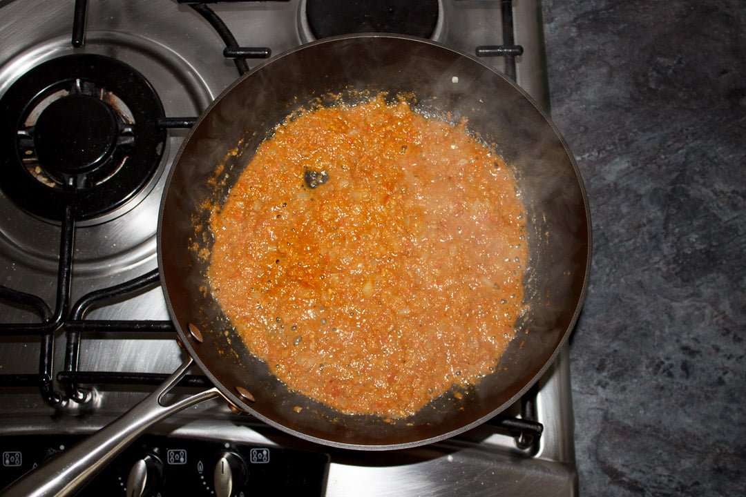 Onion frying with the tomato mixture and spices in a large saute pan