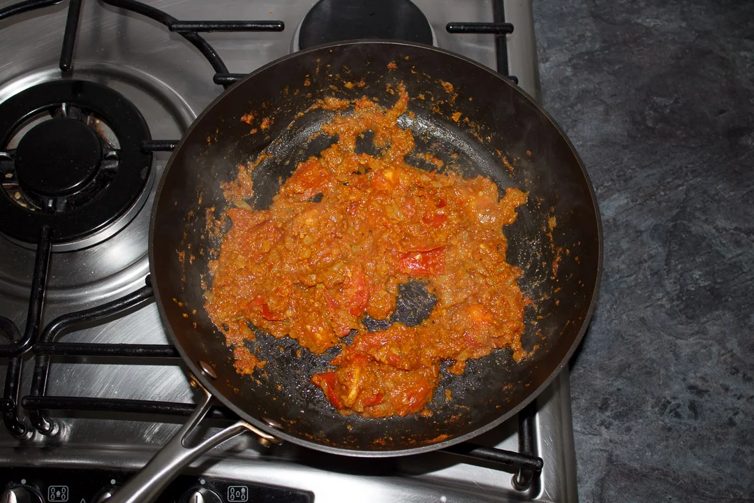 bombay aloo sauce mixture in a large saute pan with tomatoes