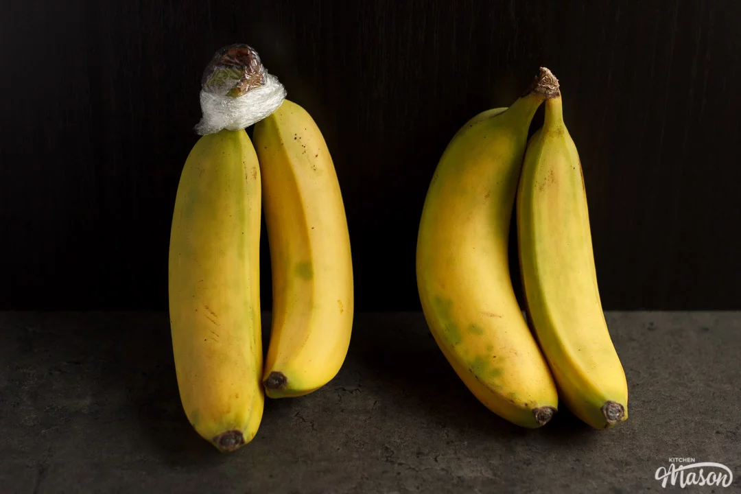 two pairs of bananas next to each other, one with the stem covered in cling film
