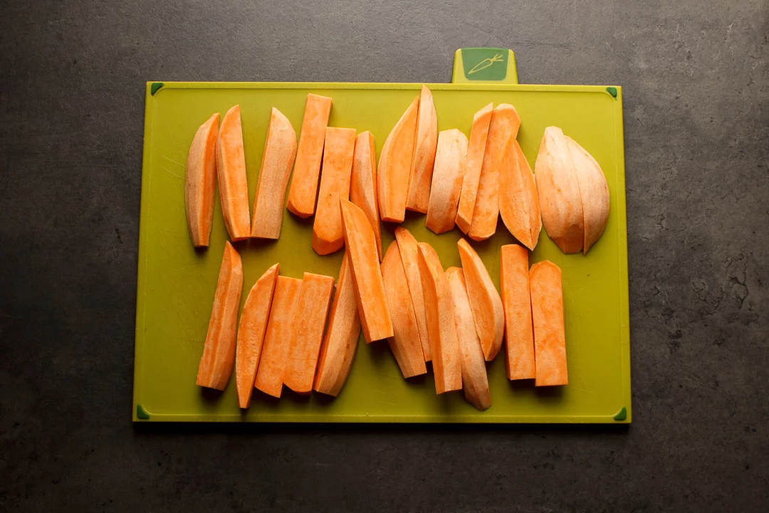 Sweet potato cut into wedges on a chopping board