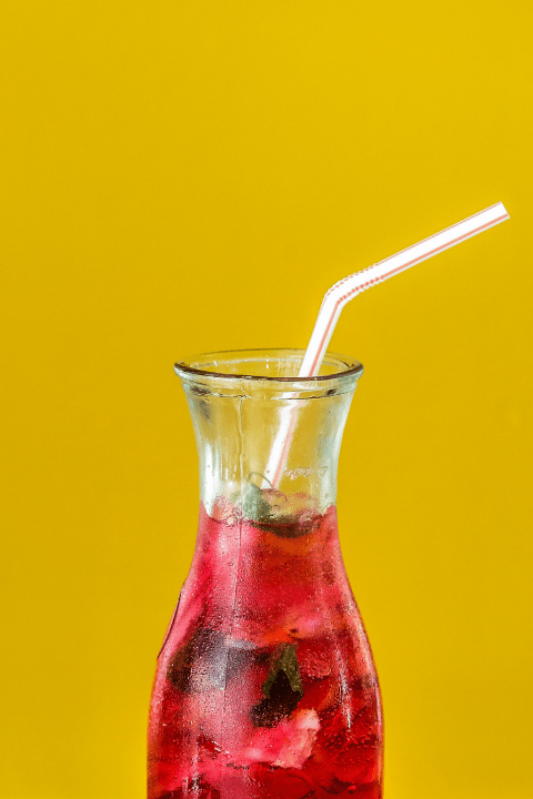 a jug with blackcurrant juice in and a straw