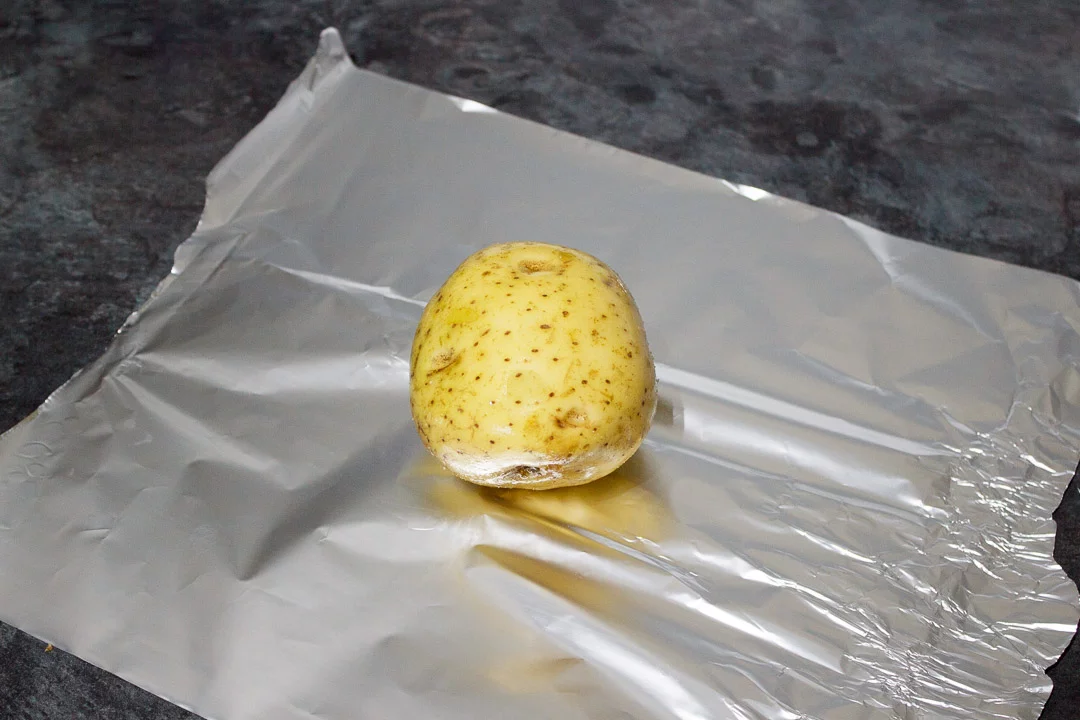 a baking potato rubbed with olive oil and salt on a sheet of foil