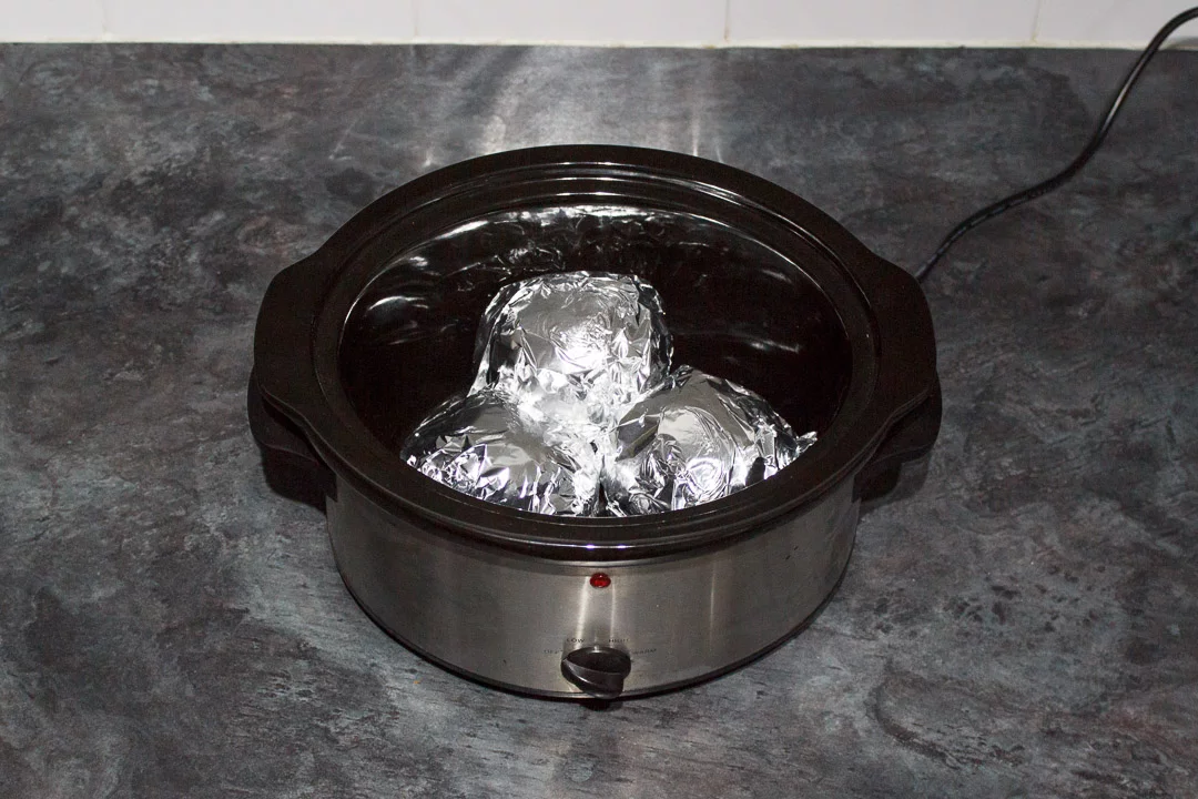 jacket potatoes wrapped in foil in a slow cooker