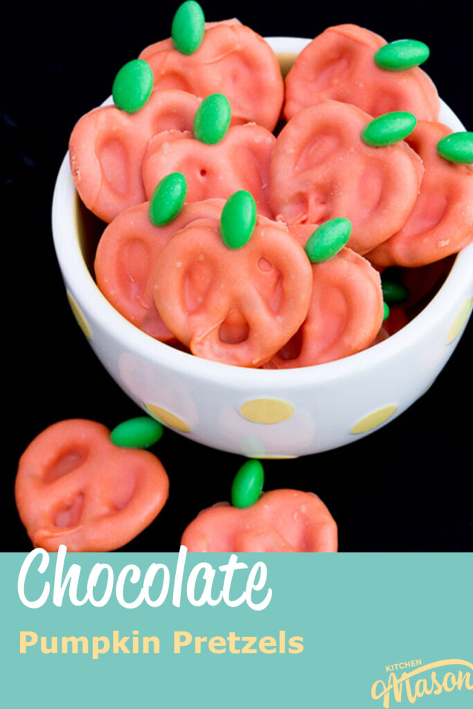 Pumpkin chocolate covered pretzels in a white bowl against a black backdrop. A text overlay says "chocolate pumpkin pretzels".