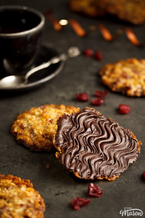 Chocolate florentines on a worktop with dried cranberries scattered around them