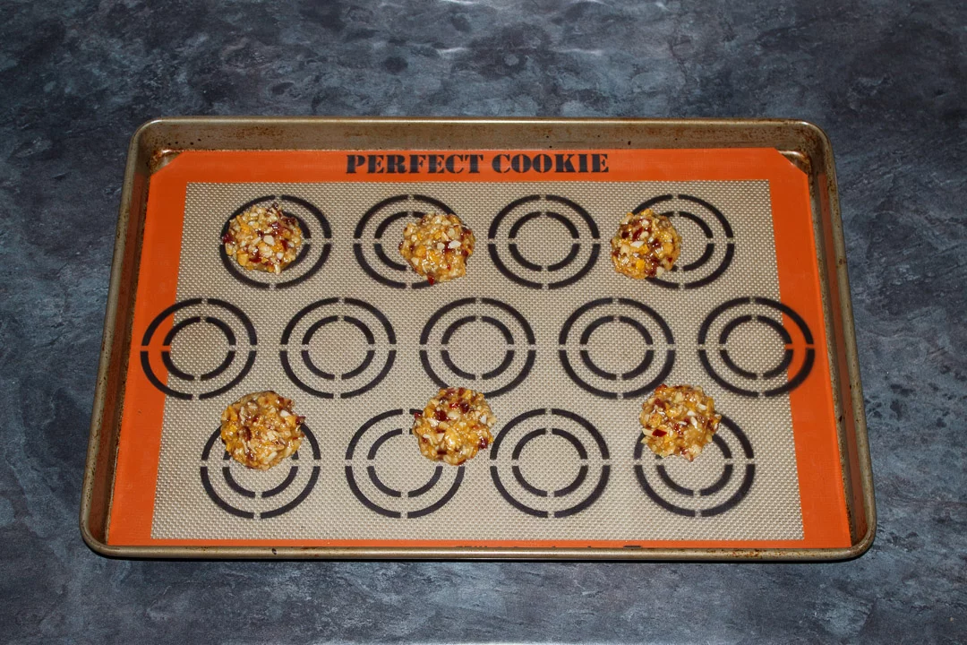small balls of florentine cookie dough spaced out on a large baking tray lined with a silicone mat
