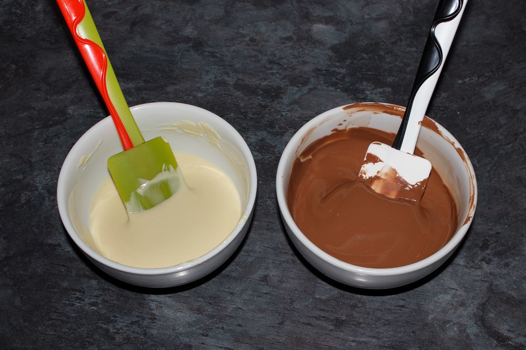 Two bowls, one with melted white chocolate and the other with melted milk chocolate