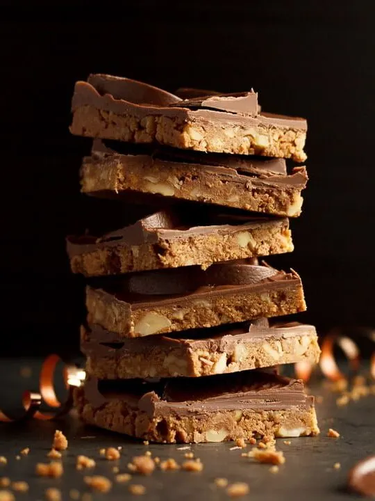 Stack of Terry's chocolate orange tiffin bars surrounded by crumbs, chocolate orange segments and curling ribbon