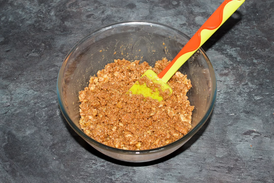 Tiffin recipe mixture in a glass bowl with chopped walnuts mixed in