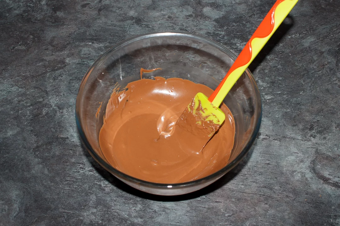 Melted Terrys chocolate orange melted in a glass bowl with a rubber spatula