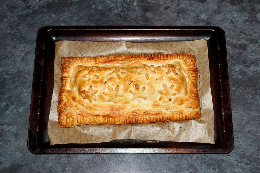 A Baked, golden vegetable wellington on a lined baking tray