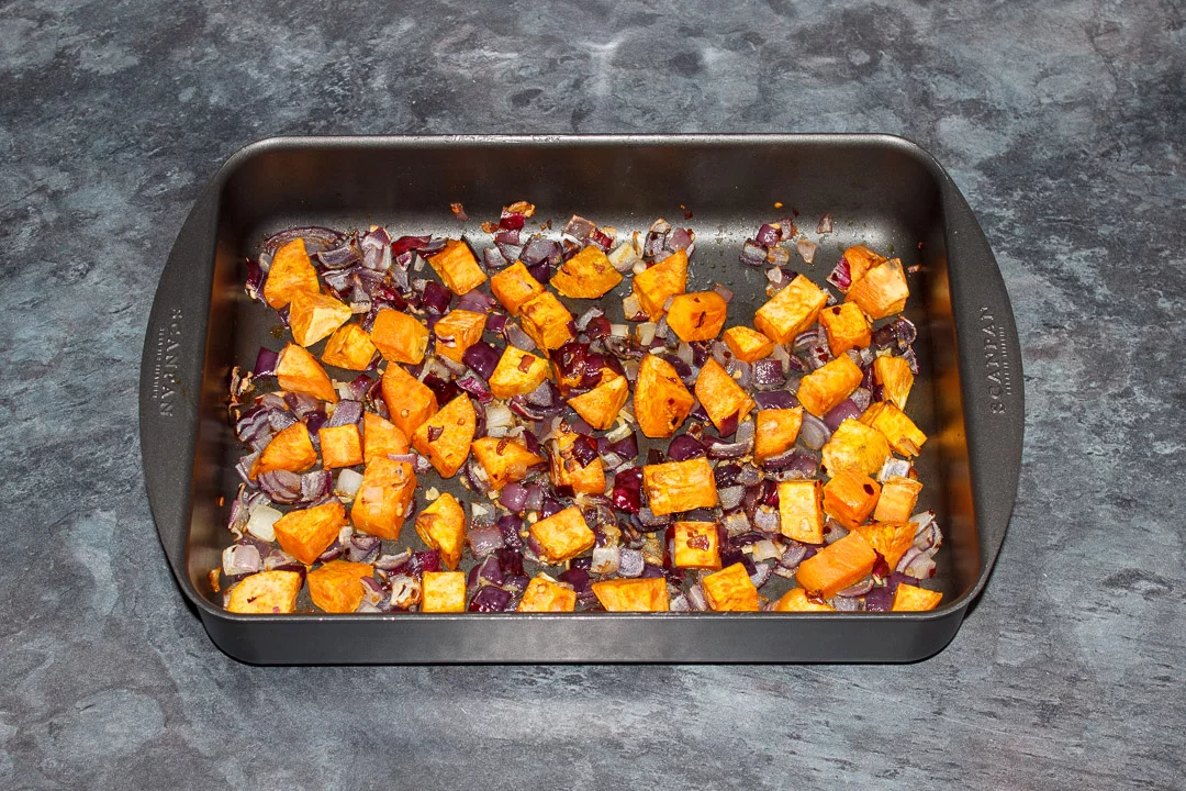 Roasted sweet potato, red onion and garlic in a roasting tray
